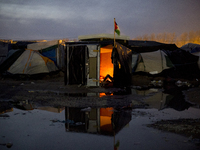 at night, a man is resting lying in his hut surrounded by water in the heart of the jungle, in Calais, northern France on February 6, 2016 ....