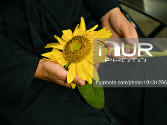 LVIV, UKRAINE - AUGUST 29, 2023 - A priest holds a sunflower that commemorates military personnel who perished during the breakthrough from...
