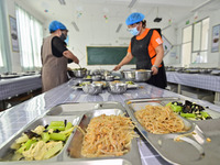 A restaurant staff distributes lunch for students at Yanghe Primary School in Gaoliu town of Qingzhou city, East China's Shandong province,...