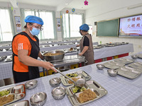 A restaurant staff distributes lunch for students at Yanghe Primary School in Gaoliu town of Qingzhou city, East China's Shandong province,...