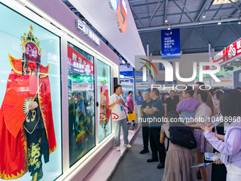  Visitors enjoy a face-changing interactive performance at the booth of CHINA Telecom at the 2023 SMART CHINA EXPO in Chongqing, China, Sept...