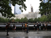 Visitors gather to pay tribute to the victims of 9/11 attacks near one of two reflecting pools at the National September 11 Memorial & Museu...
