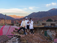 Three young people stand on a pile of rubble in the village of Ijoukak, which has been completely leveled by the earthquake. (