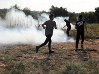 Palestinian protesters flee from tear gas during clashes with Israeli forces in a demonstration along the border between the Gaza Strip and...
