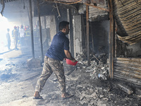 A shop owner tries to extinguish a fire that broke out, at the Mohammadpur Krishi Market in Dhaka, Bangladesh, on September 14, 2023.
 (
