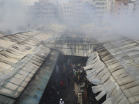 
Firefighters and volunteers are seen at the Mohammadpur Krishi Market, while smoke rises after a massive fire broke out, in Dhaka, Banglad...