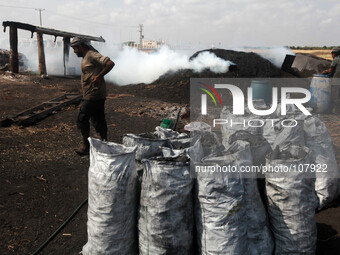 Palestinian charcoal workers take a lunch break at the production facility, in Gaza CIty, on May 12, 2014. (