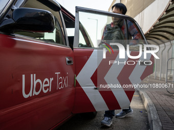 A man entering a Taxi with Uber Taxi advertisement on it at a taxi stand on November 21, 2023 in Hong Kong, China. Around 500 Hong Kong Taxi...