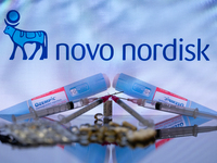 The Novo Nordisk pharmaceutical logo is being displayed on a screen alongside pills and a medical vial with a syringe in this photo illustra...