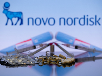 The Novo Nordisk pharmaceutical logo is being displayed on a screen alongside pills and a medical vial with a syringe in this photo illustra...