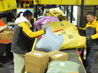 Staff members at an e-commerce logistics industrial park are sorting express parcels on an assembly line at an express transfer center in Li...