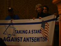 Attendees are holding protest signs as Governor Josh Shapiro and Senator Bob Casey join local community leaders to rally against antisemitis...