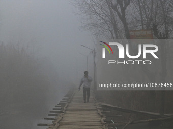 A man is walking on a wooden bridge in the interiors of Dal Lake amid a cold and foggy day in Srinagar, Kashmir, India, on December 26, 2023...
