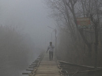 A man is walking on a wooden bridge in the interiors of Dal Lake amid a cold and foggy day in Srinagar, Kashmir, India, on December 26, 2023...