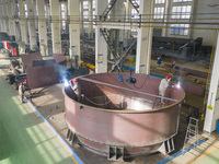 A worker is producing large waste incineration equipment for export at an environmental energy workshop in Hai'an, Jiangsu Province, China,...