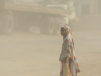 A girl is walking on a dusty and heavily polluted road in Dhaka, Bangladesh, on December 2023. (