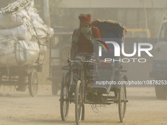 A rickshaw puller is riding on a dusty and heavily polluted road in Dhaka, Bangladesh, in December 2023. (
