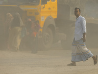 People are walking on a dusty and heavily polluted road in Dhaka, Bangladesh, on December 2023. (