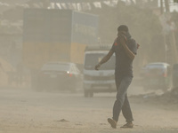 A man is walking on a dusty and heavily polluted road in Dhaka, Bangladesh, on December 2023. (
