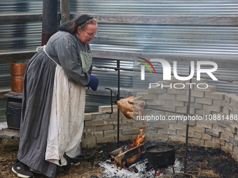 A woman is cooking a chicken on a rotisserie over a fire in Woodbridge, Ontario, Canada, on October 7, 2023. (