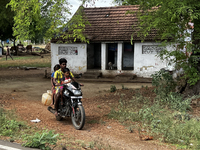 A man is driving on a motorbike with his wife and child in Nilakkottai, Tamil Nadu, India. (