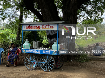 A woman is waiting for customers at a small juice cart along the roadside in Nilakkottai, Tamil Nadu, India. (