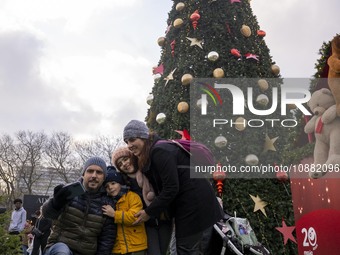 A group of people is taking a selfie in front of a Christmas pine tree at a fair in Eduardo VII Park, Lisbon, Portugal, on December 30, 2023...
