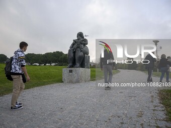 A group of people is walking near a statue by Colombian sculptor Fernando Botero located on the grounds of Eduardo VII Park in Lisbon, Portu...