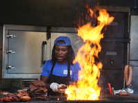 A man is barbecuing racks of ribs and chicken on a large grill at the Northern Heat Rib and Beer Festival in Vaughan, Ontario, Canada, on Au...