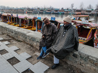 Shikara or boat owners are sitting on the banks of Dal Lake as they wait for tourists in Srinagar, Jammu and Kashmir, India, on January 3, 2...