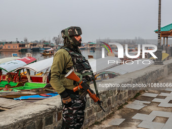 A CRPF trooper is standing alert on the banks of Dal Lake on a cold day in Srinagar, India, on January 3, 2023. (