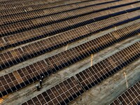 Workers are checking the operation of a photovoltaic array for power generation at the new energy base in Zhangye, Gansu Province, China, on...