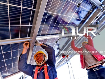 Builders are installing photovoltaic panels at the construction site of a 100,000 kW photovoltaic power generation project in Zhangye, China...