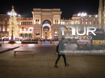 A person is walking in Piazza Duomo (Duomo Square), against the backdrop of the facade of Galleria Vittorio Emanuele II, in Milan, Italy, du...