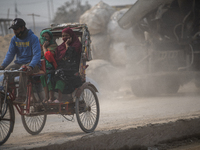 People are moving along a dusty, busy road in Dhaka, Bangladesh, on January 18, 2024. (