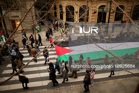 Protesters are carrying a large Palestinian flag in support of Palestine and against the Israeli government's actions in the Gaza Strip duri...