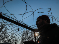 A man is looking on as concertina wire is being installed on a metallic fence in Sopore District, Baramulla, Jammu and Kashmir, India, on Ja...