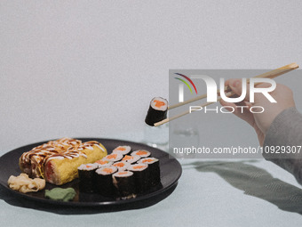 A woman is eating banana sushi rolls and salmon maki sushi rolls in Athens, Greece, on January 21, 2024. (
