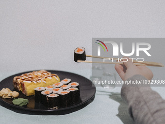 A woman is eating banana sushi rolls and salmon maki sushi rolls in Athens, Greece, on January 21, 2024. (