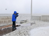 A tourist is taking photos of the frozen scene at the seaside in Yantai, China, on January 22, 2024. (