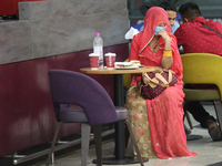 A woman dressed in a saree is having a snack while waiting for a flight at Indira Gandhi International Airport in Delhi, India, on May 3, 20...