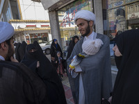 An Iranian cleric is carrying his child while standing with his relatives on a sidewalk in the holy city of Qom, 145 km (90 miles) south of...