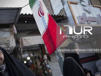 Two veiled Iranian women are standing under an Iranian flag that is hanging on a sidewalk in the holy city of Qom, 145 km (90 miles) south o...