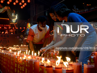 A woman is lighting candles and offering prayers for good fortune to mark the Lunar New Year of the Dragon at Dhanagun Temple in Bogor, West...