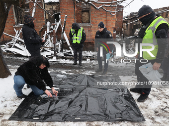 Law enforcers are standing by human remains pouches spread on the ground in the Nemyshlianskyi district in Kharkiv, Ukraine, on February 10,...
