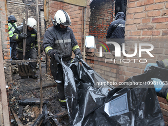 Rescuers are carrying a body bag with the remains of a victim from a fire-stricken house in the Nemyshlianskyi district after the Russian dr...