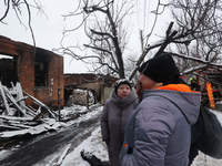 A psychologist from the State Emergency Service is talking to a crying woman at a fire-stricken house in the Nemyshlianskyi district after t...