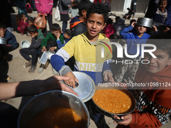 Displaced Palestinians are receiving food at a donation point in a refugee camp in Deir al-Balah, central Gaza Strip, on February 10, 2024,...