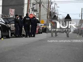 A vehicle is being struck by gunfire, and several shell casings are lying in the street on 12th Avenue in Paterson, New Jersey, United State...