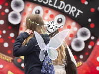 Two carnival revelers are walking past a carnival float before the traditional Rose Monday parade in Duesseldorf, Germany, on February 12, 2...